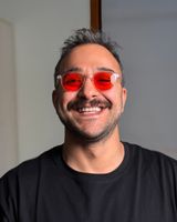Dr. Can Çiftçi, turuncu camlı gözlüğüyle gülümsüyor